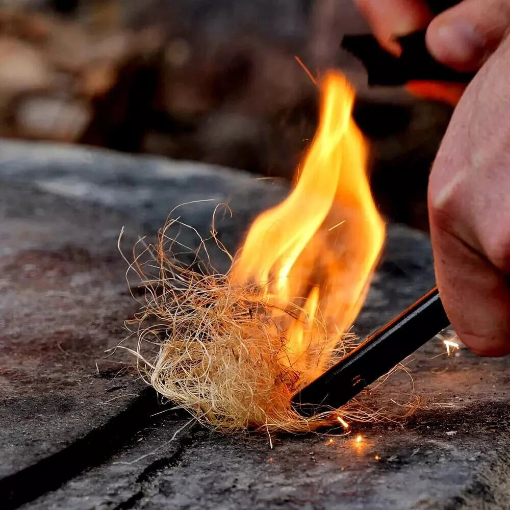 Person using a huge ferro rod to ignite dry grass on a stone surface
