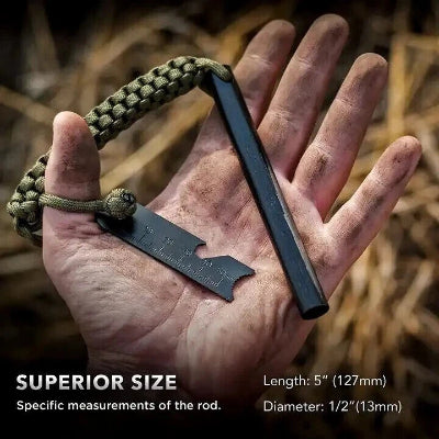 Hand holding a huge black 5" inch by 1/2 inch black ferro rod with measurements, surrounded by natural elements.