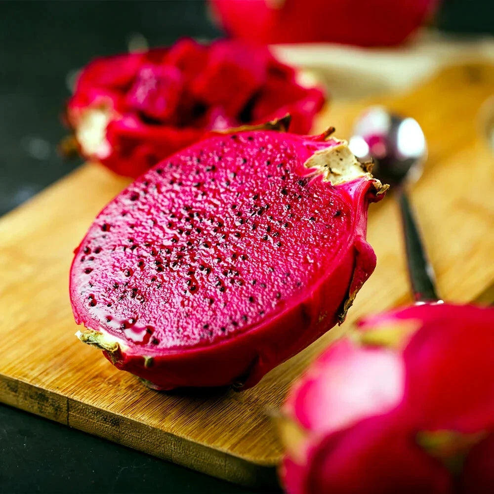 Sliced red dragon fruit on a wooden cutting board with a spoon